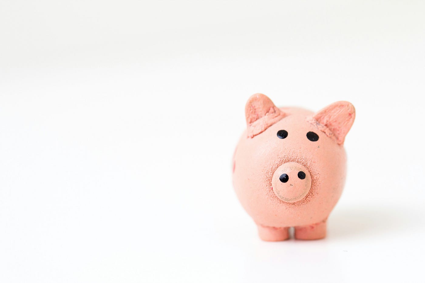 A small pink ceramic piggy bank standing alone against a plain white background.