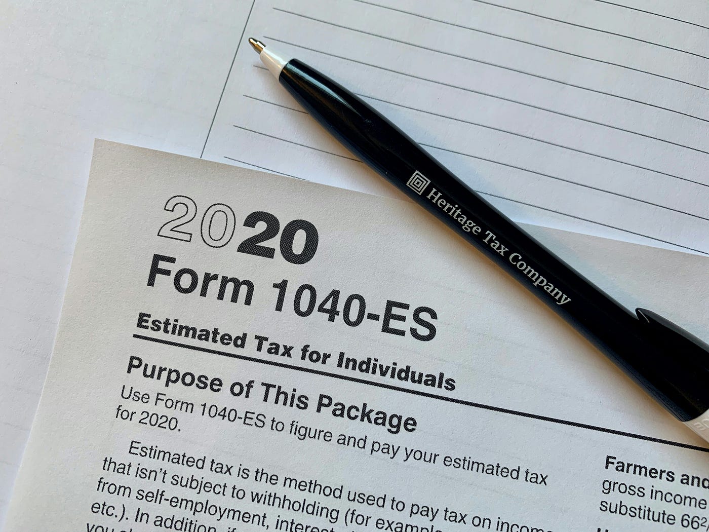 A printed tax form headed '2020 Form 1040-ES, Estimated Tax for Individuals', with a branded ballpoint pen resting across it.