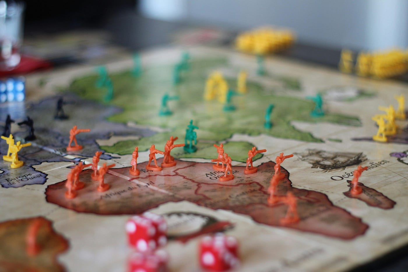 A game of Risk mid-play: coloured plastic army pieces massed across a map of Africa and Europe, dice scattered in the foreground.