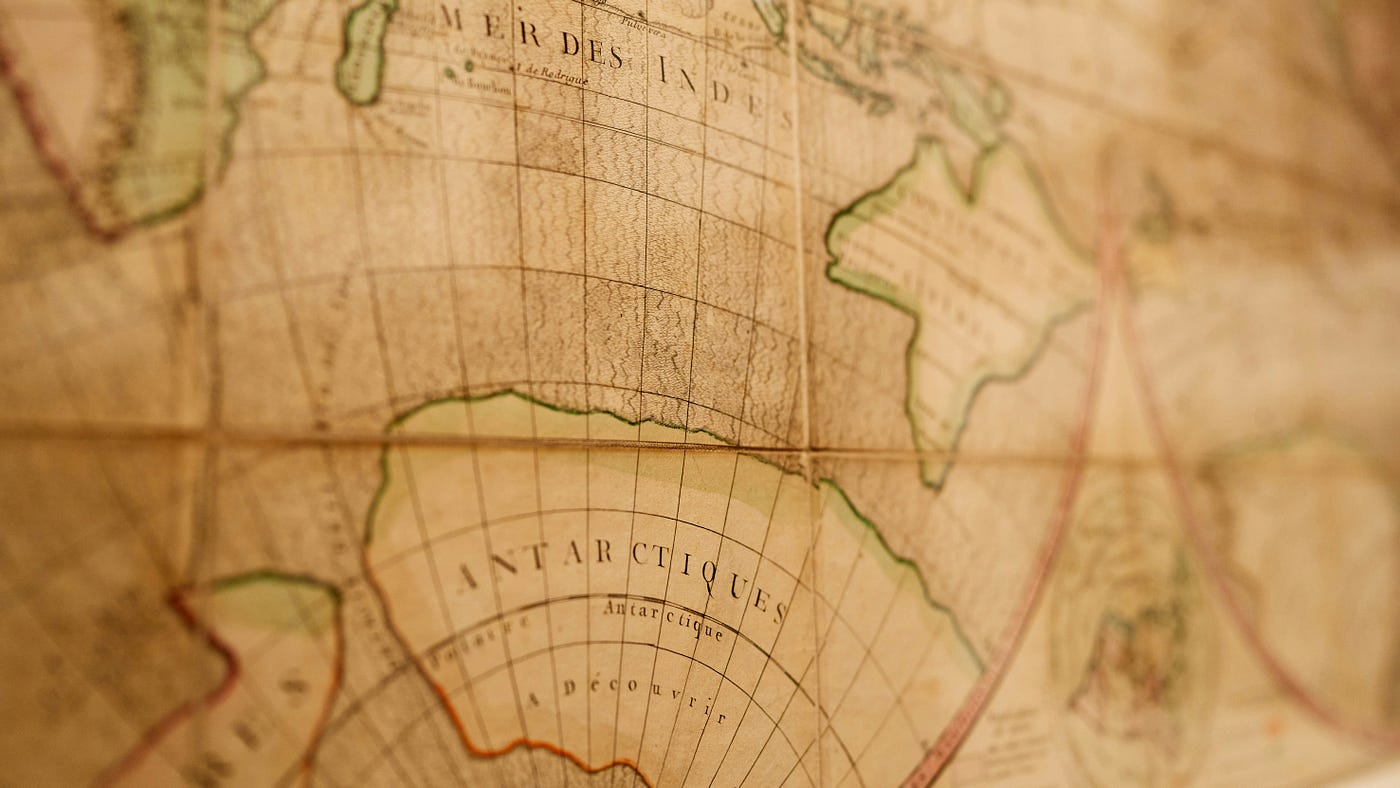 Close-up of an antique globe, shallow focus across the Indian Ocean and an Antarctic coastline labelled 'à découvrir' — still to be discovered.